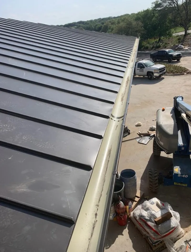 Standing seam panel and gutter detail on a metal roofing jobsite in Swanton